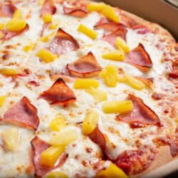 Pizza, jossa juustoa, ananasta ja kinkkua.